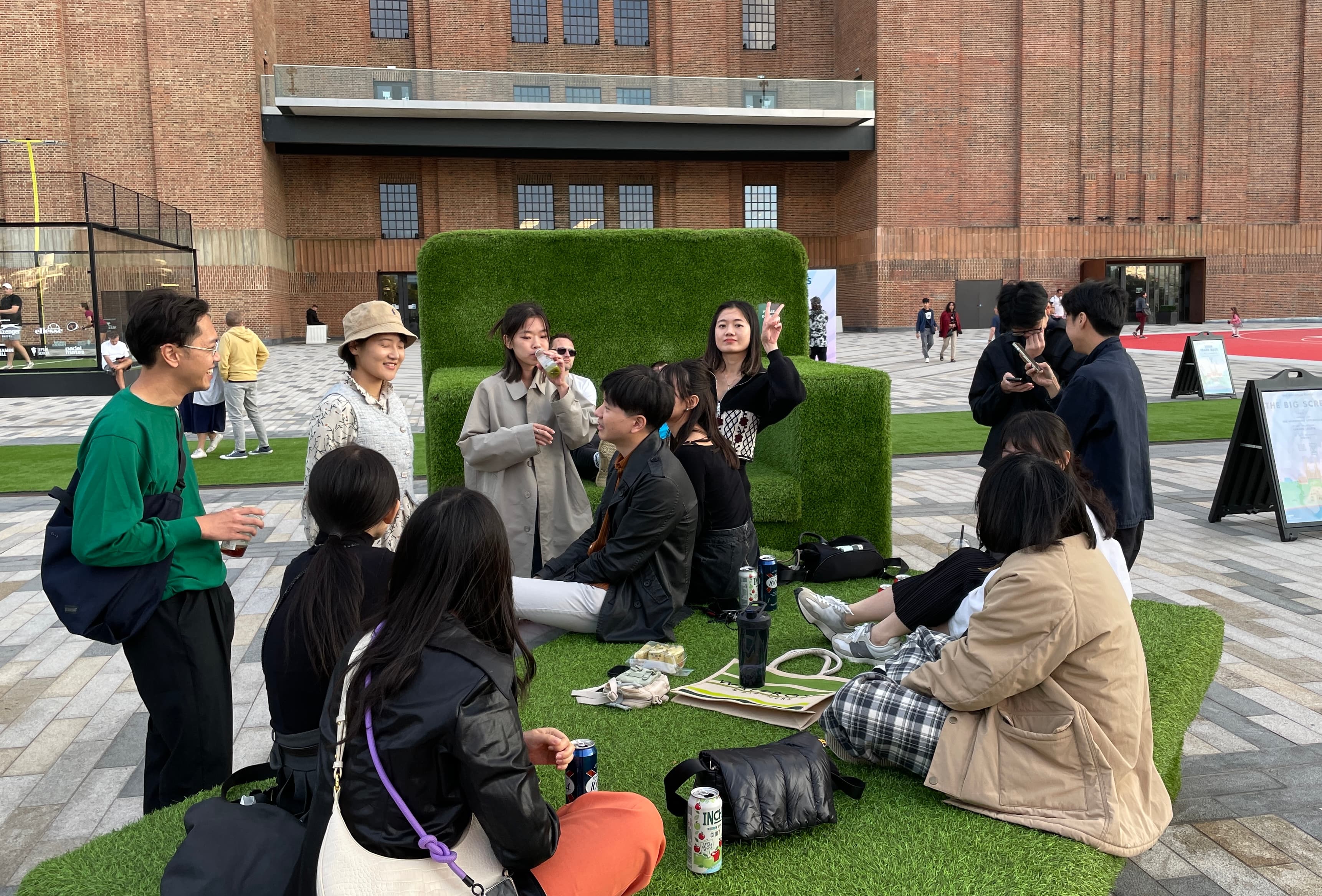 Taiwanese students of the RCA class of 2023–24 gathering to meet each other on the grass outside Battersea Power Station
