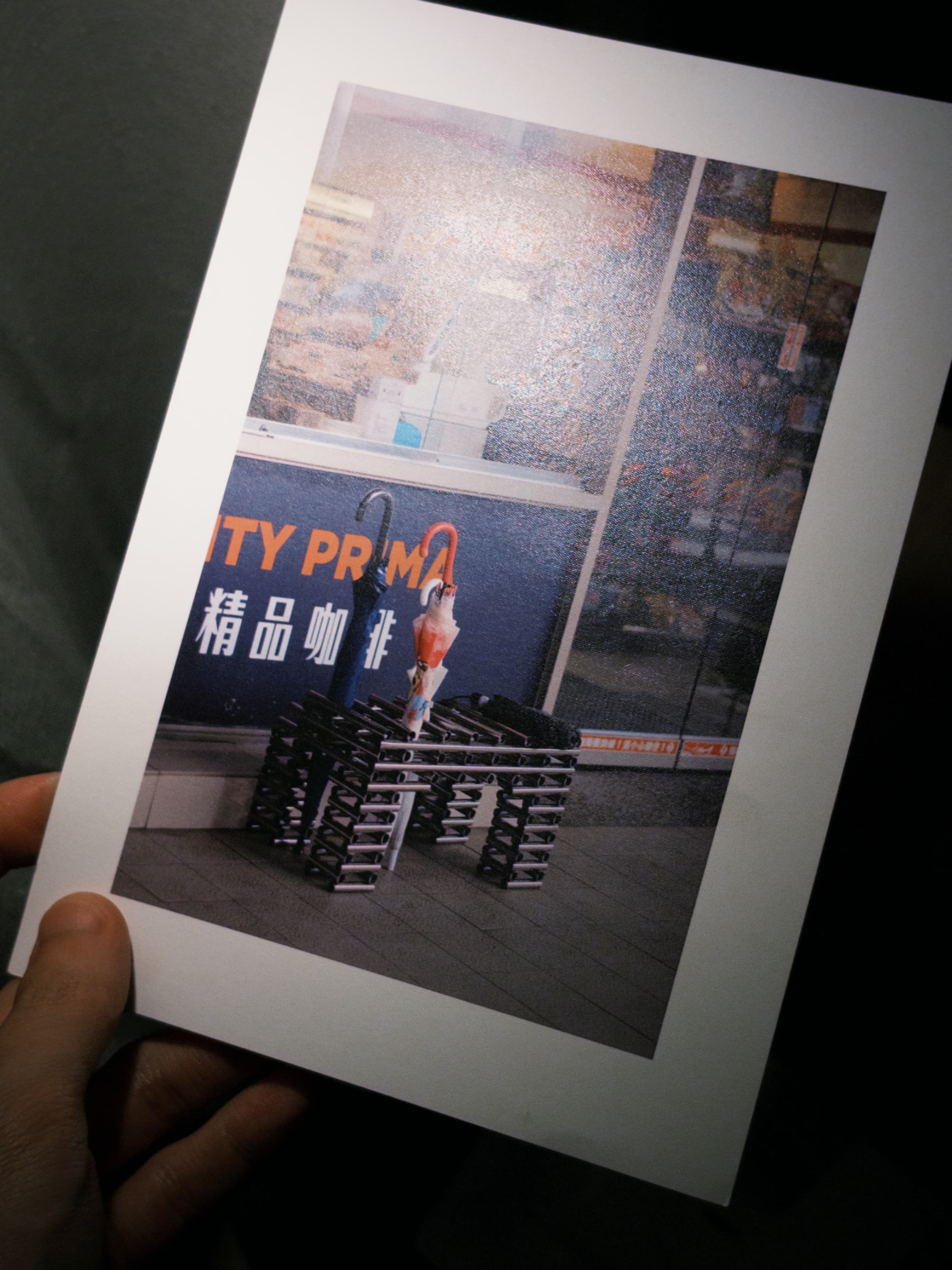 Group final project from Prof Hsu-Wei Huang's social design course: a photograph mounted on white matte board, showing an umbrella slotted into a public umbrella rack outside a street-side speciality coffee shop
