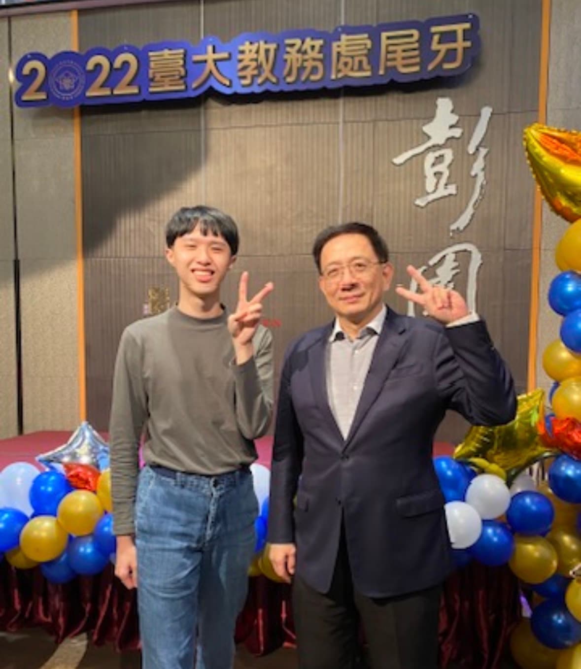 A photo with then-NTU-President Kuan Chung-Ming at the 2022 NTU Office of Academic Affairs year-end party, in front of the event's red banner