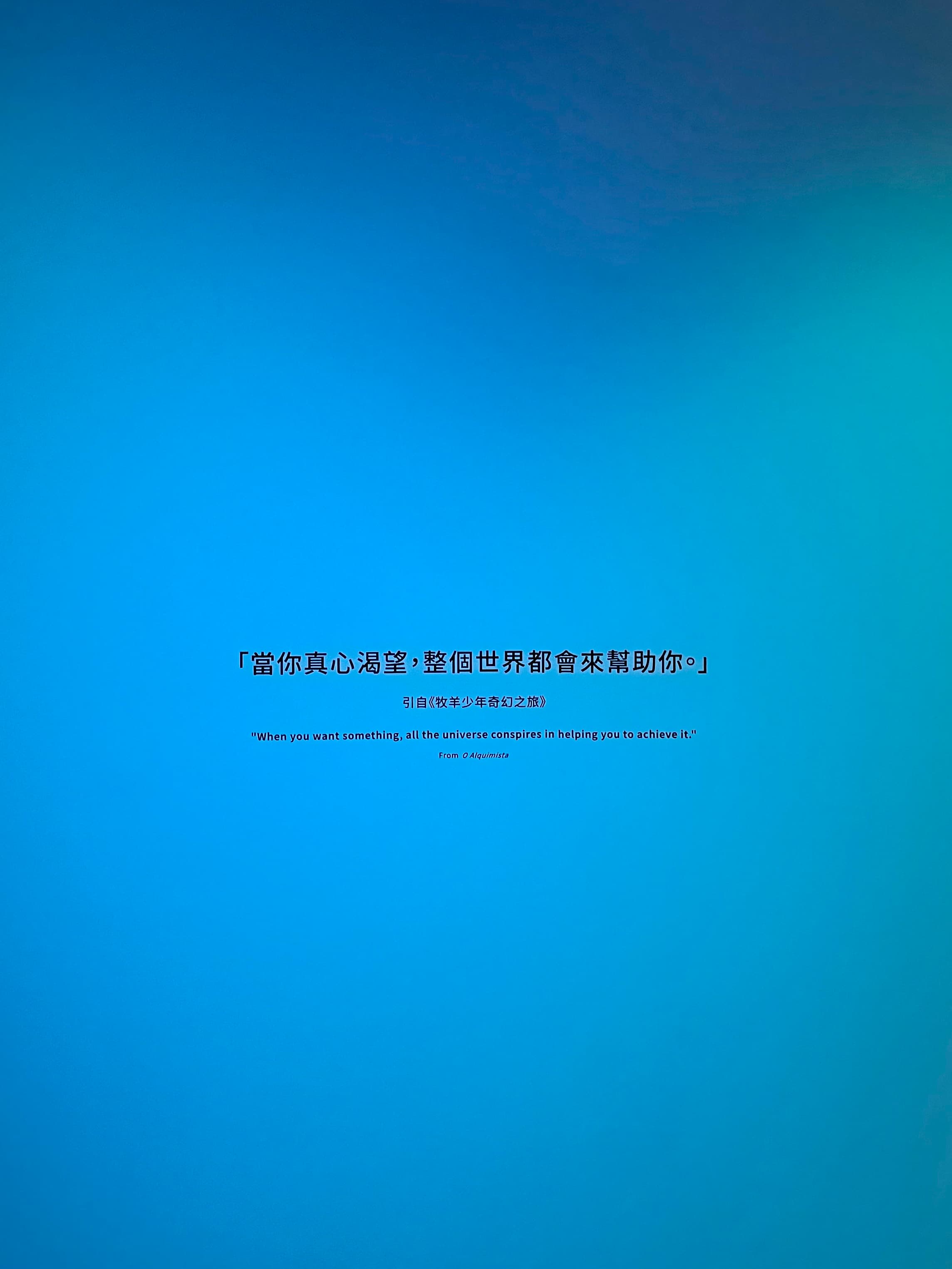 藍色漸層背景上的策展論述文字:「當你真心渴望,整個世界都會來幫助你。」引自牧羊少年奇幻之旅